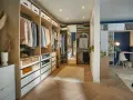 Un dressing DIY bien organisé avec des étagères en bois, des tiroirs blancs et des vêtements suspendus. Un espace fonctionnel pour ranger vos affaires.