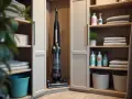 Un aspirateur trône dans un coin de ce rangement balai fait maison, à côté de produits ménagers et de serviettes pliées.