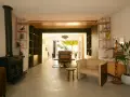 Aménagement maison en longueur : salon avec poêle, étagères et vue sur salle à manger et jardin.