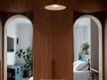 Deux arches arche maison en bois de noyer encadrent une chambre avec un lit blanc et un salon avec une télévision.
