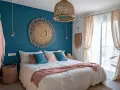 Chambre avec deco bleu canard et bois. Un grand soleil mural en paille, coussins bleus et roses, et un plaid pêche sur le lit.