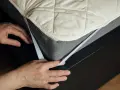 Mains ajustant un protège-matelas matelassé sur un sommier. Comprendre la différence protège matelas et alèse pour un sommeil optimal.