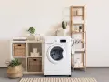 Une buanderie bien aménagée avec une machine à laver, des paniers en osier, des étagères en bois et des plantes vertes pour une touche de fraîcheur.