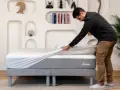 Un homme installe une housse sur un matelas, assurant ainsi sa protection.