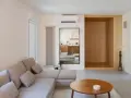 Salon épuré avec canapé modulable, table basse en bois et un coin boisé rappelant une maison style japonais en France.