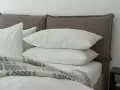 Lit douillet avec deux oreillers blancs empilés, une couverture à motifs et un drap housse ou protège matelas immaculé.