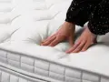 Mains testant la douceur d'un matelas blanc matelassé. Quel matelas pour mal de dos dur ou mou ? Le confort est essentiel.