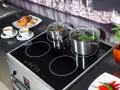 Plaque à induction moderne avec deux casseroles en marche, symbolisant la puissance et l'efficacité. Deux tasses de café et des viennoiseries sont prêtes pour le petit-déjeuner.