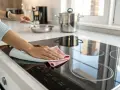 Main d'une personne effectuant le nettoyage de sa plaque induction avec un chiffon doux.