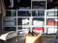 Des vêtements pliés dans des tiroirs transparents, une solution pour optimiser rangement vetements. Des chaussures marron sur une table basse.