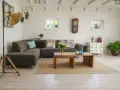 Un salon moderne avec poutre apparente, canapé confortable, table basse en bois et murs en briques blanches.