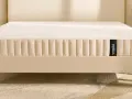 Un matelas hybride Wopilo sur un sommier beige aux pieds en bois. Quel sommier pour matelas hybride ? Ce lit offre un confort optimal.