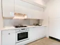 Cuisine moderne blanche avec hotte intégrée au-dessus de la plaque de cuisson. La hauteur de la hotte cuisine est idéale pour une utilisation confortable.