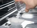 Maintenant, vous savez ou mettre le sel dans le lave vaisselle. Une main verse des pastilles de sel dans le compartiment prévu à cet effet.