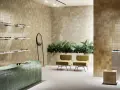 Un espace moderne avec des murs recouverts de **zellige** beige, un comptoir vert émeraude, des plantes luxuriantes et des chaises jaunes.