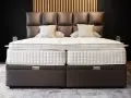 Lit, deux matelas blancs sur des sommiers marron. Le matelas trop grand pour sommier crée un léger débord.