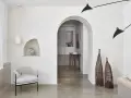 Un salon moderne avec un arche en pierre, un fauteuil gris, des lampes noires et un habillage arche maison.