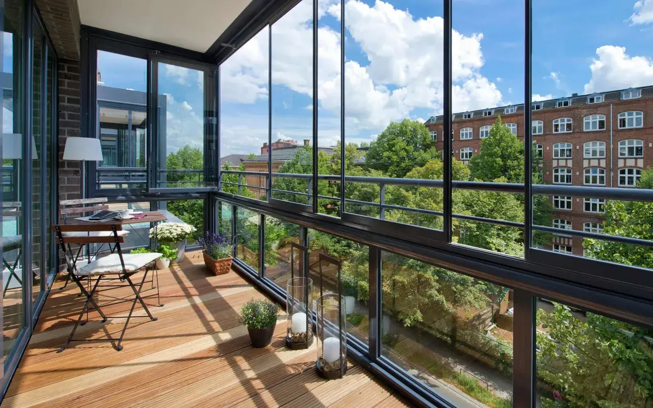 Un espace de vie lumineux avec une loggia balcon vitrée, un coin repas et une vue sur la verdure et les bâtiments.