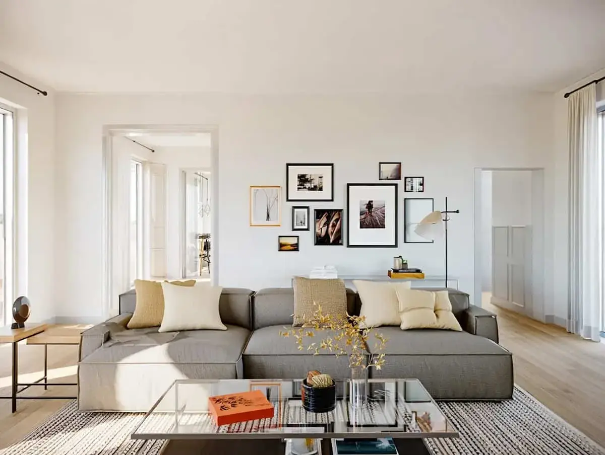 Un salon moderne avec un grand canapé gris, des coussins beiges et une galerie de cadres photo. Une excellente idée déco salon pour une ambiance chaleureuse.