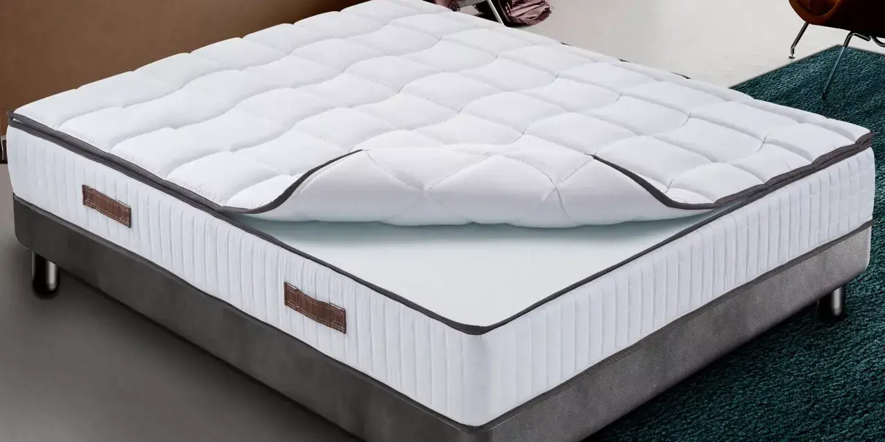 Un matelas king size mémoire de forme, blanc matelassé, sur un sommier gris. Confort garanti pour des nuits paisibles.