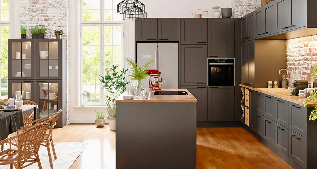 Cuisine moderne avec îlot central et armoires sombres. Un réfrigérateur non encastrable est discrètement intégré dans le décor.