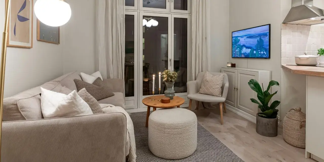Salon cosy avec canapé, fauteuil, table basse et pouf. Une astuce rangement petit appartement : le meuble bas sous la TV optimise l'espace.