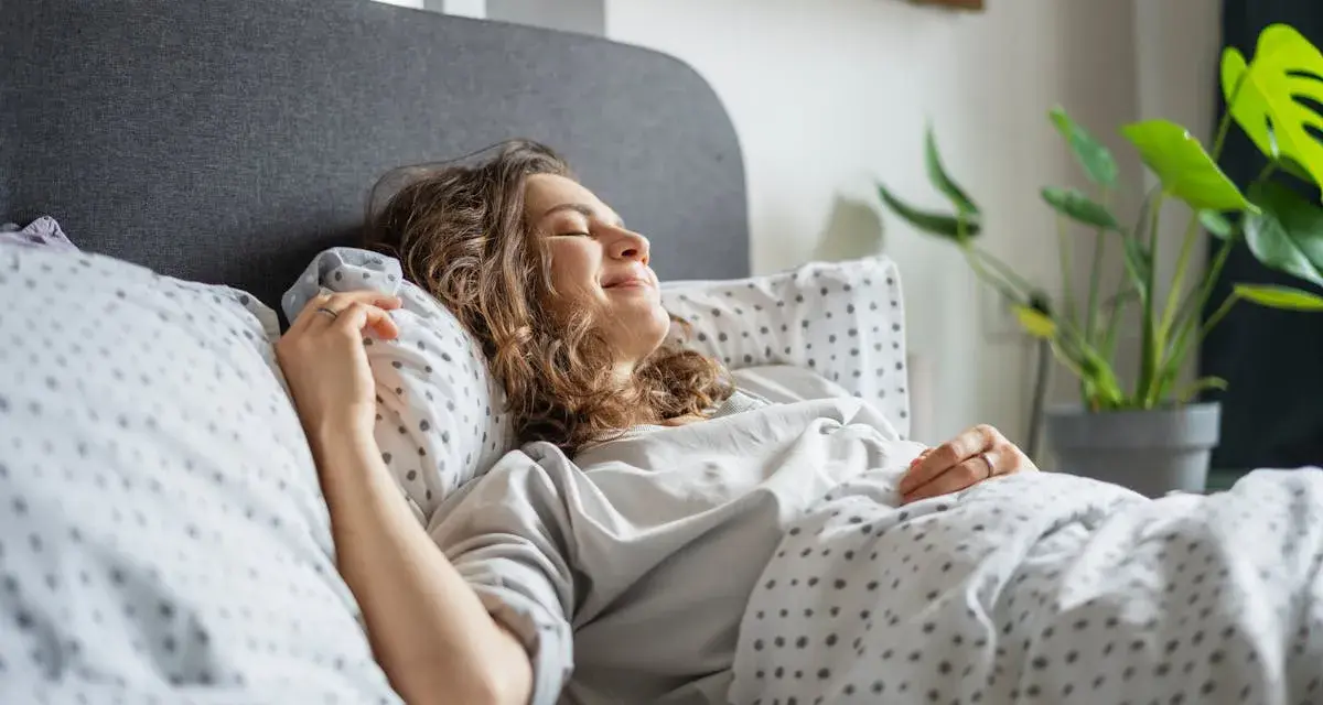 Une femme souriante se repose dans un lit douillet. Elle semble heureuse, une belle illustration de comment choisir une bonne literie pour un sommeil réparateur.