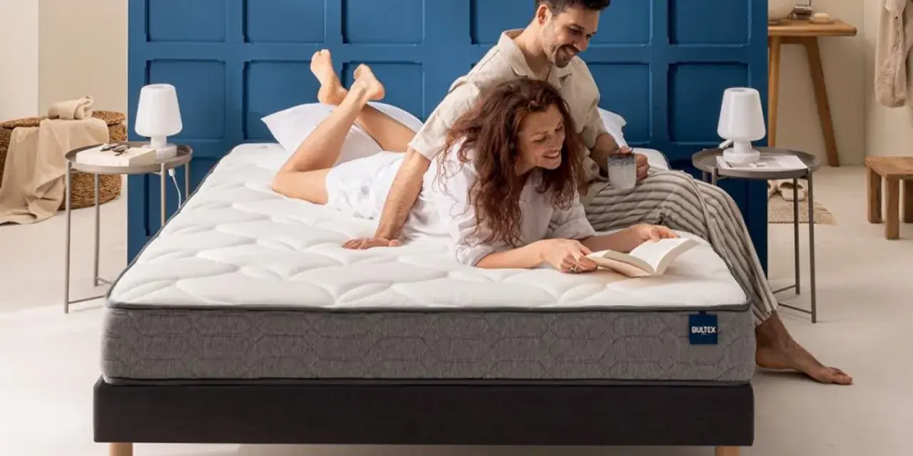 Un couple profite d'un moment de détente sur un matelas de taille lit 2 places. L'homme lit, la femme lit un livre.