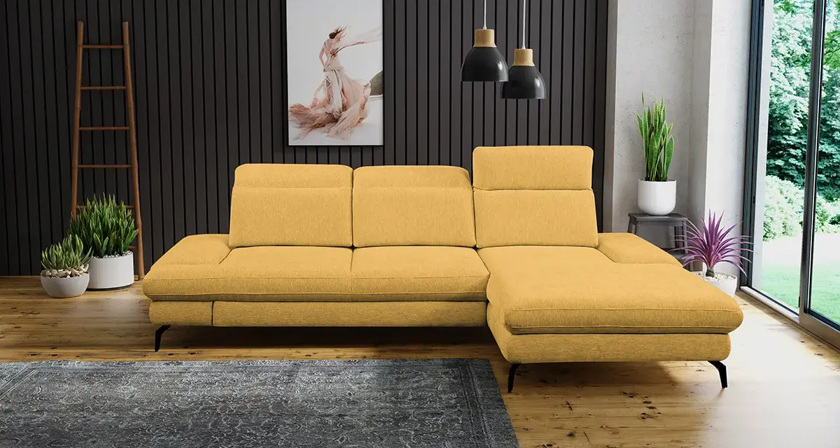 Un salon moderne avec un canapé jaune moutarde, un tapis gris foncé et des plantes vertes. Quelle couleur associer avec un canapé jaune moutarde ? Le gris est une excellente option.