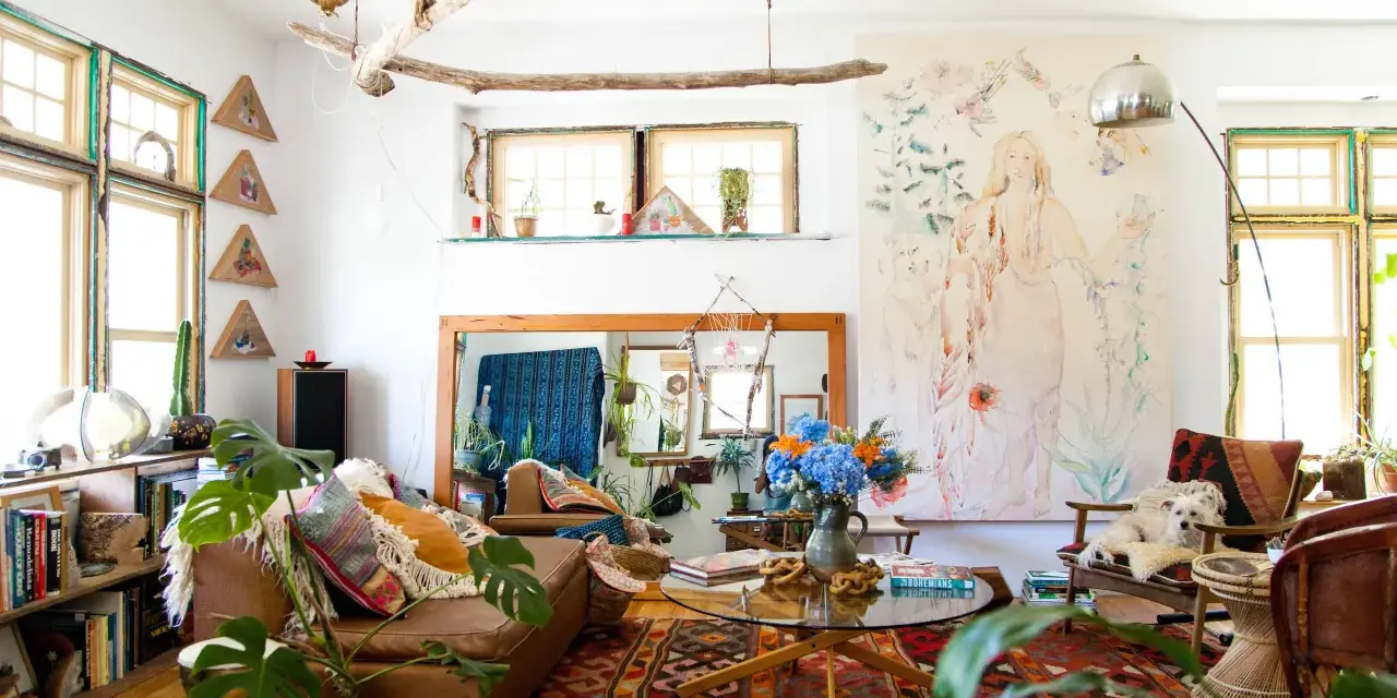 Salon bohème, style kinfolk, avec tapis ethnique, canapé en cuir, plantes vertes et un tableau mural.