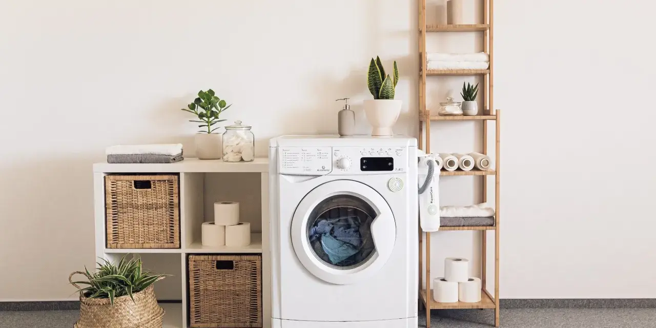 Une buanderie bien aménagée avec une machine à laver, des paniers en osier, des étagères en bois et des plantes vertes pour une touche de fraîcheur.