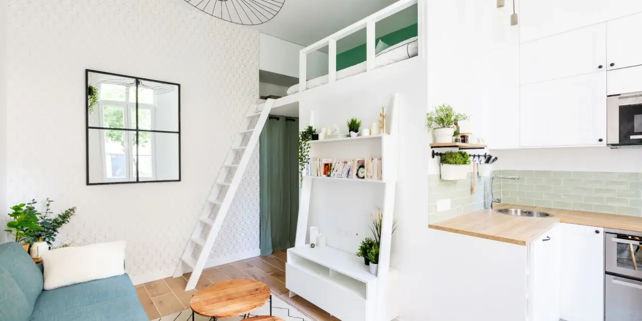 Plan studio 20m2 en longueur : canapé bleu, tables basses rondes, étagères, lit mezzanine accessible par échelle, cuisine compacte.