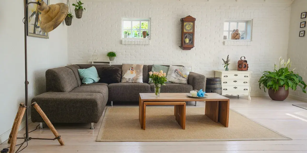 Un salon moderne avec poutre apparente, canapé confortable, table basse en bois et murs en briques blanches.