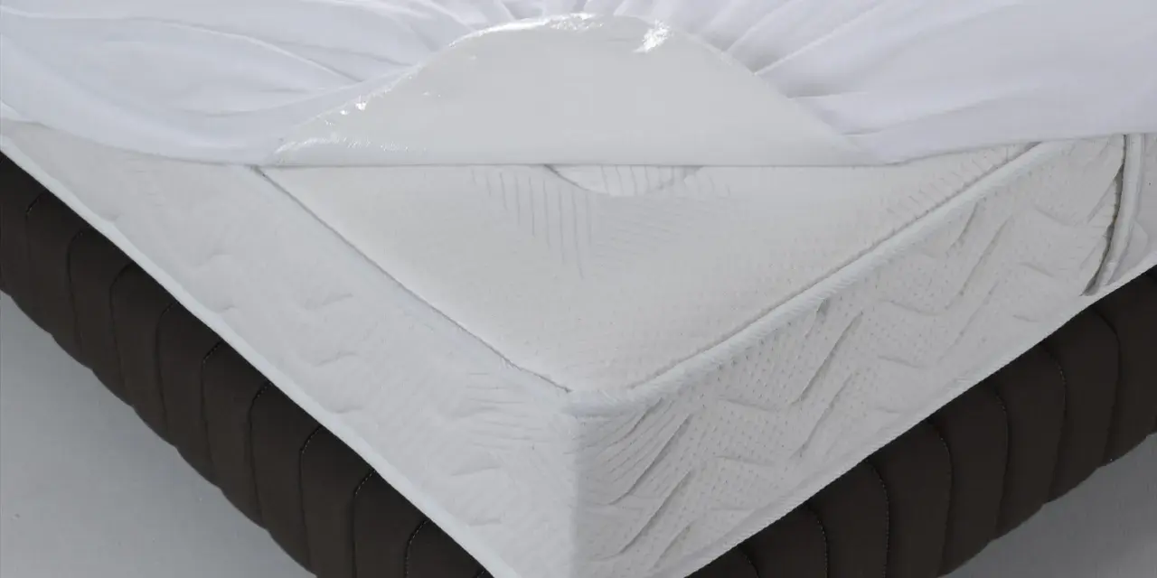 Un matelas blanc avec une alèse imperméable soulevée, montrant de quel côté mettre une alèse pour protéger le matelas.