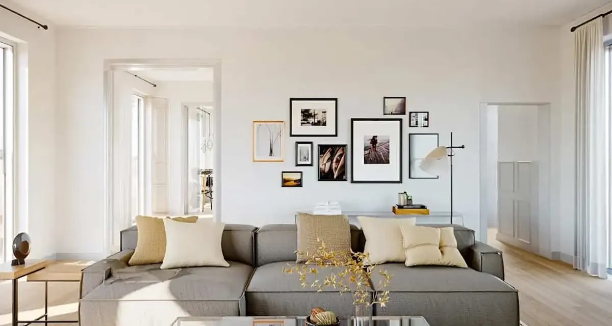 Un salon moderne avec un grand canapé gris, des coussins beiges et une galerie de cadres photo. Une excellente idée déco salon pour une ambiance chaleureuse.