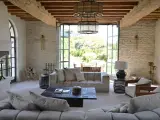 L'intérieur d'un mas provençal baigné de lumière, avec des poutres apparentes, des murs en pierre et une vue imprenable sur la campagne.