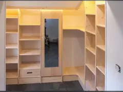 Construction d'une armoire sur mesure avec des portes coulissantes et des étagères en bois clair. Un miroir est intégré.