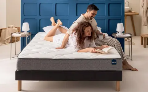 Un couple profite d'un moment de détente sur un matelas de taille lit 2 places. L'homme lit, la femme lit un livre.