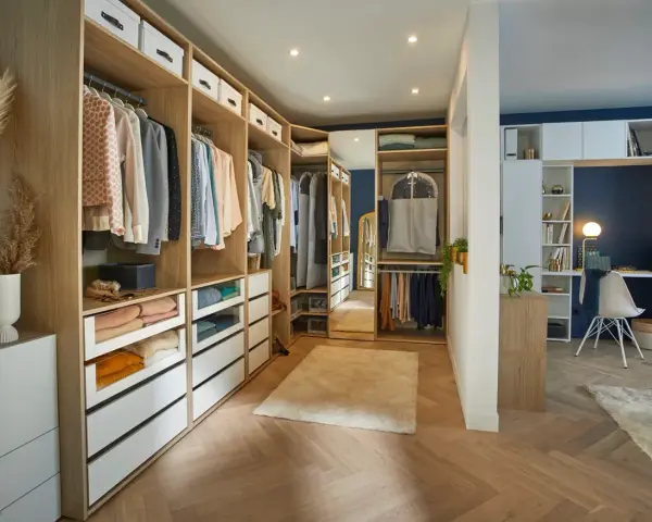 Un dressing DIY bien organisé avec des étagères en bois, des tiroirs blancs et des vêtements suspendus. Un espace fonctionnel pour ranger vos affaires.