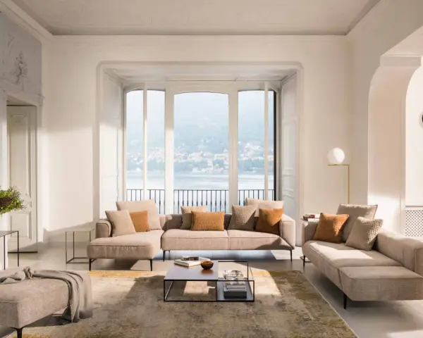 Un salon cocooning chaleureux avec un grand canapé d'angle, des coussins douillets et une vue imprenable sur un lac.