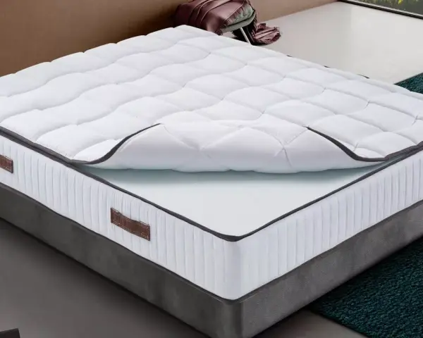 Un matelas king size mémoire de forme, blanc matelassé, sur un sommier gris. Confort garanti pour des nuits paisibles.