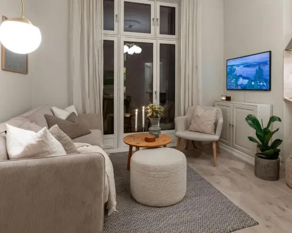Salon cosy avec canapé, fauteuil, table basse et pouf. Une astuce rangement petit appartement : le meuble bas sous la TV optimise l'espace.