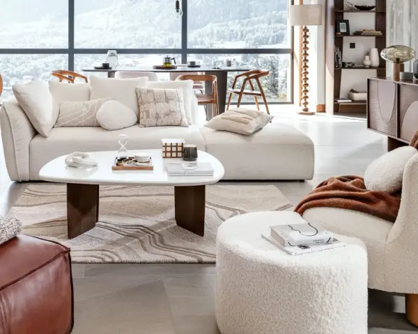 Un confortable salon d'hiver avec un canapé moelleux, une table basse design et une vue panoramique sur les montagnes enneigées.