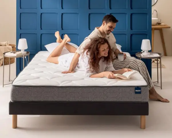 Un couple profite d'un moment de détente sur un matelas de taille lit 2 places. L'homme lit, la femme lit un livre.