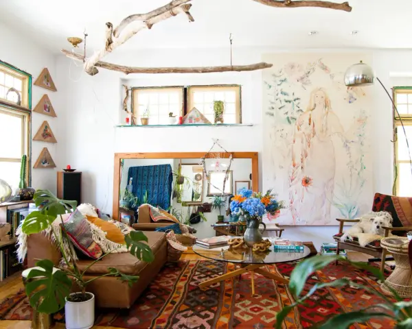 Salon bohème, style kinfolk, avec tapis ethnique, canapé en cuir, plantes vertes et un tableau mural.