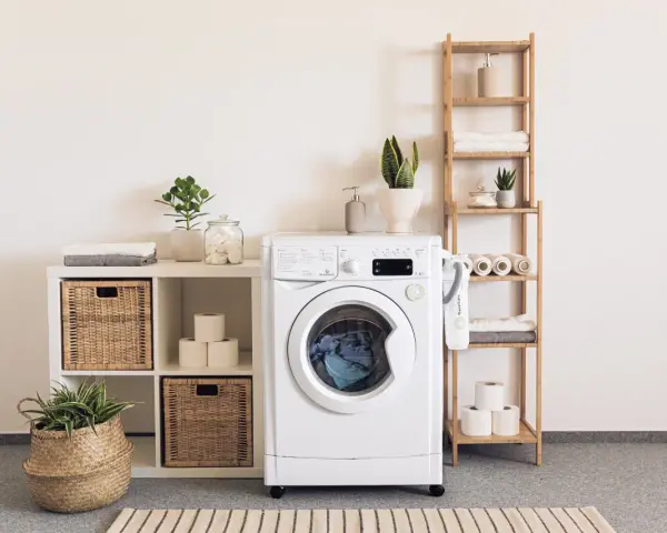 Une buanderie bien aménagée avec une machine à laver, des paniers en osier, des étagères en bois et des plantes vertes pour une touche de fraîcheur.