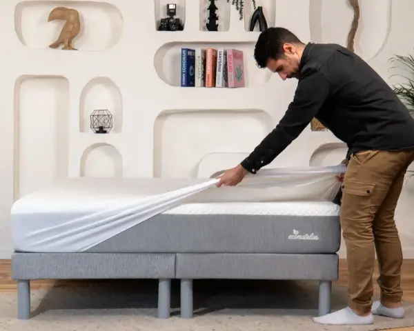 Un homme installe une housse sur un matelas, assurant ainsi sa protection.