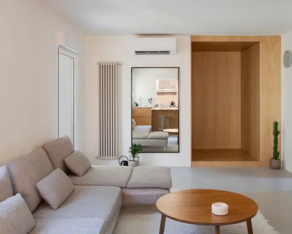 Salon épuré avec canapé modulable, table basse en bois et un coin boisé rappelant une maison style japonais en France.