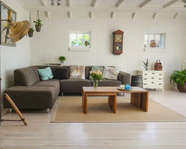 Un salon moderne avec poutre apparente, canapé confortable, table basse en bois et murs en briques blanches.