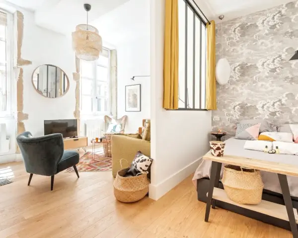 Une belle idée séparation chambre salon avec un mur décoré de nuages et un coin salon cosy.